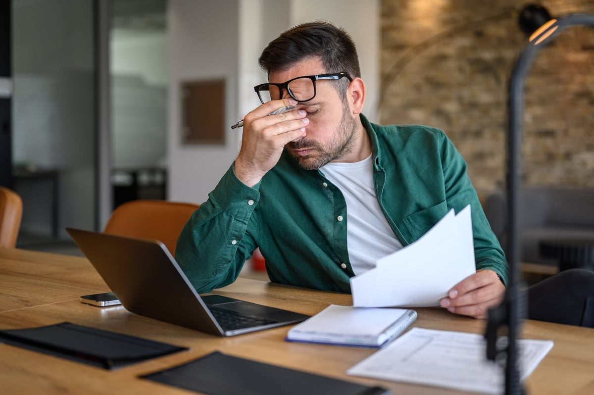 Male financial advisor working over laptop and analyzing reports at desk