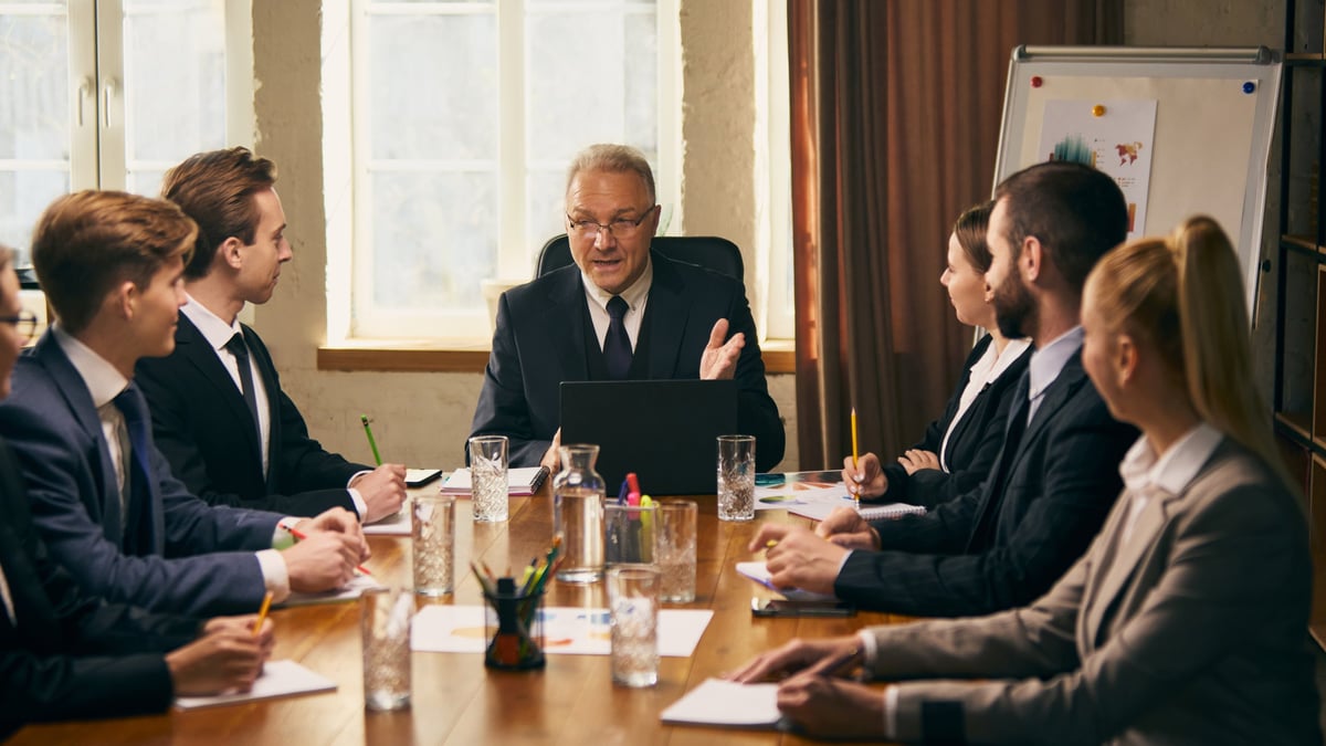 Senior business leader presenting during an executive meeting with financial documents visible