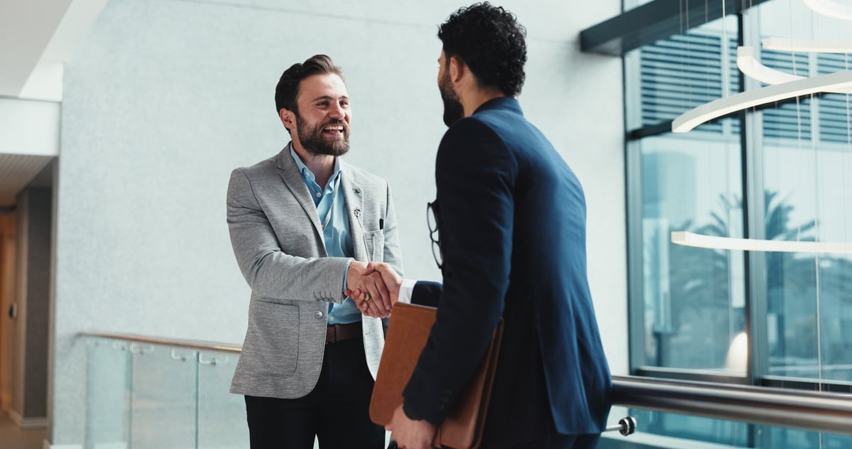 Collaboration, handshake and meeting with business people at window in office for partnership