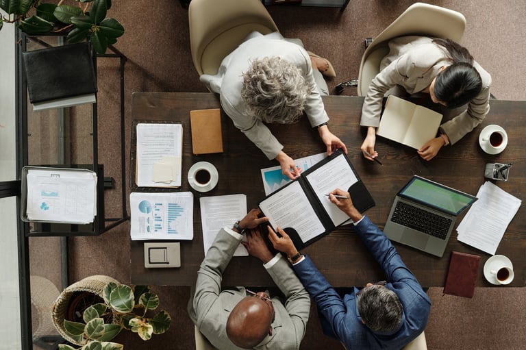 Business professionals reviewing vendor contracts and procurement documents around a table