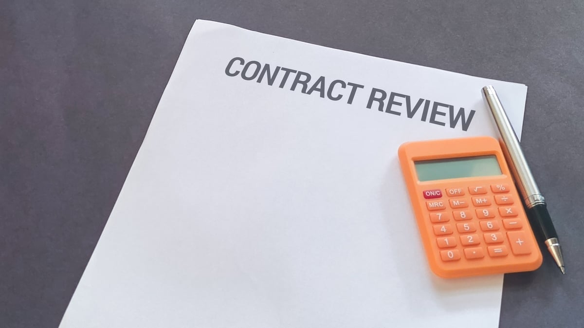 Contract review document prepared for examination with pen and calculator for vendor pricing analysis